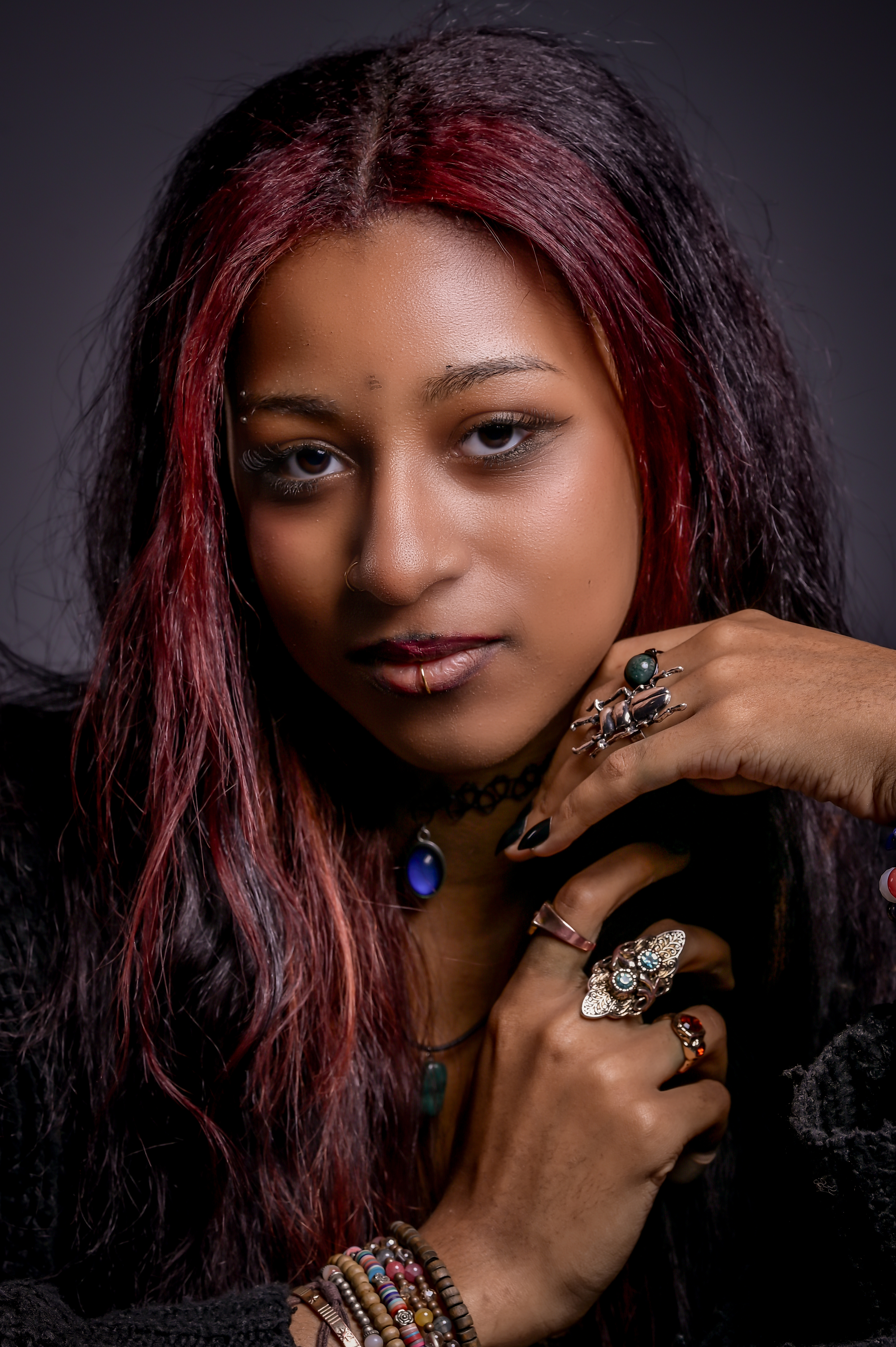 Close portrait of Alanna Crouch with red hair against a dark studio background.